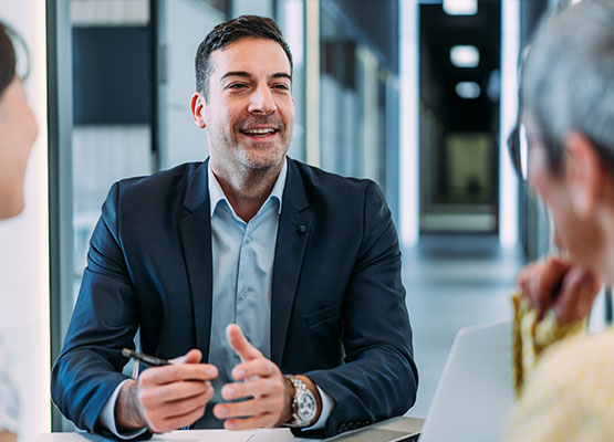 Man in a Suit Smiling and Talking with Two People