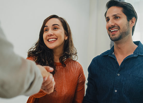 Happy couple shaking hands with loan officer