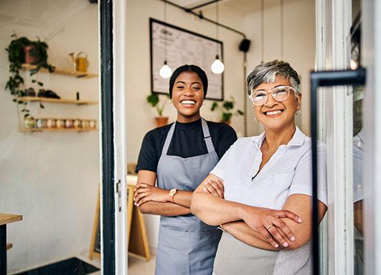 Two woman smiling at the doorway of a business