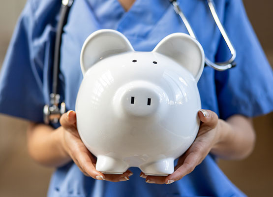 Person in Medical scrubs holding piggy bank